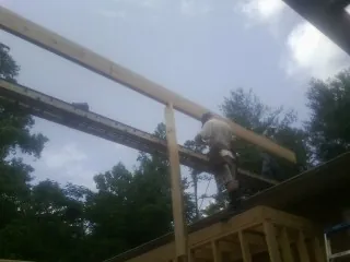 Carpenter setting a ridge beam over a new addition frame — Ice Dam Removal by Roofing Brothers in San Andreas