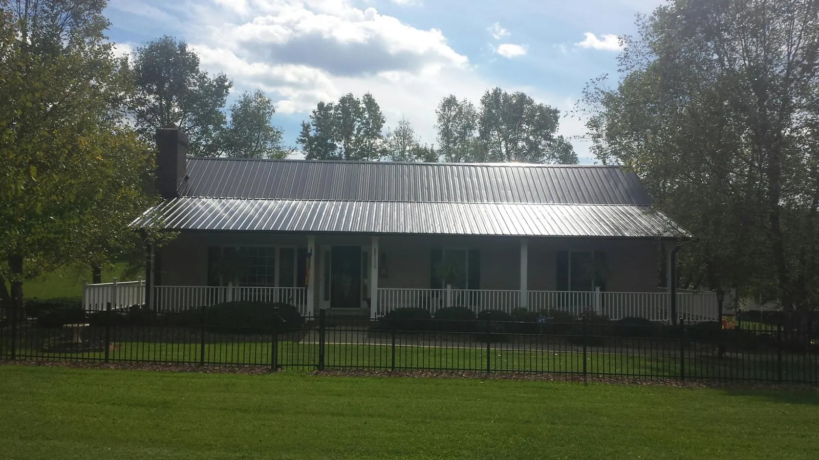 Gray metal roof on a brick ranch with a full width front porch — Gutter Guard Installation work by our crew in San Andreas