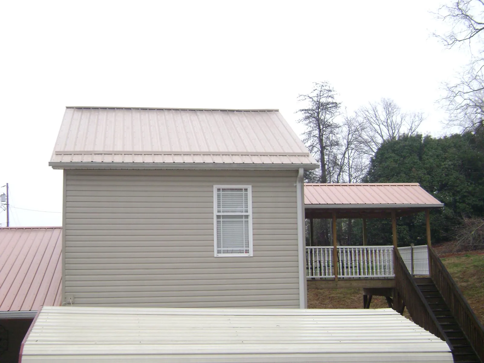 Tan metal roofs on a two story addition and attached porch, from a Roof Replacement job in San Andreas