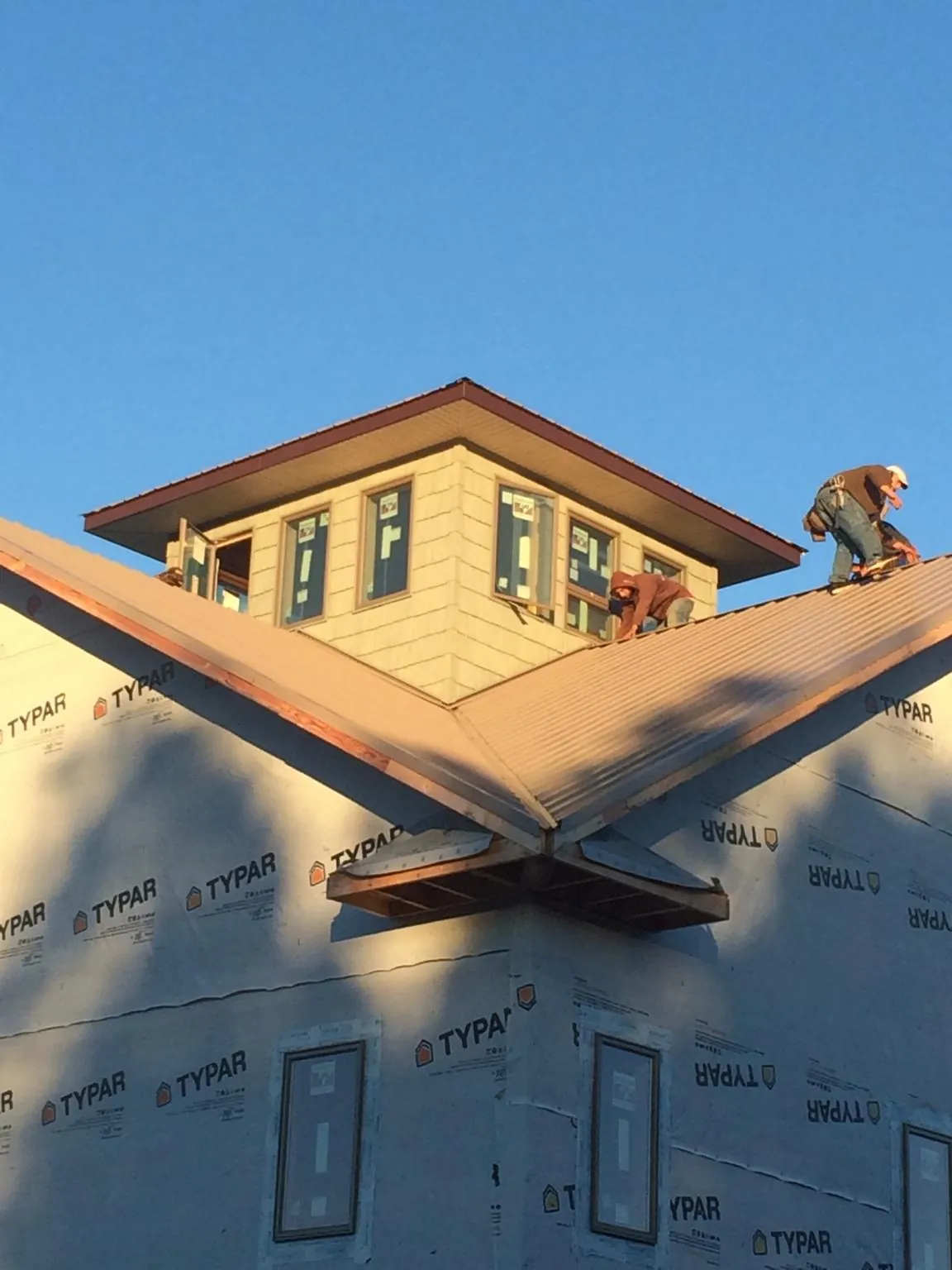 Roofers working around a rooftop cupola on a new metal roof at sunset — Roof Waterproofing in San Andreas by Roofing Brothers